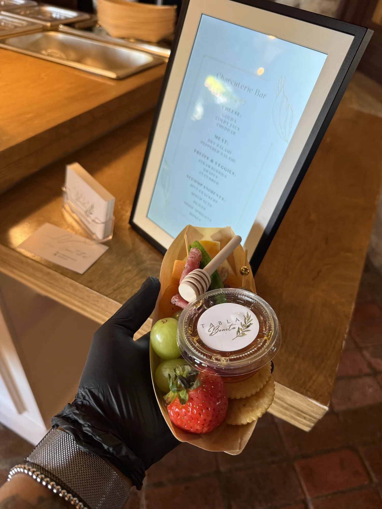 Charcuterie cone with salami, cheese, grapes, a strawberry, crackers and a Tabla Bonita honey cup