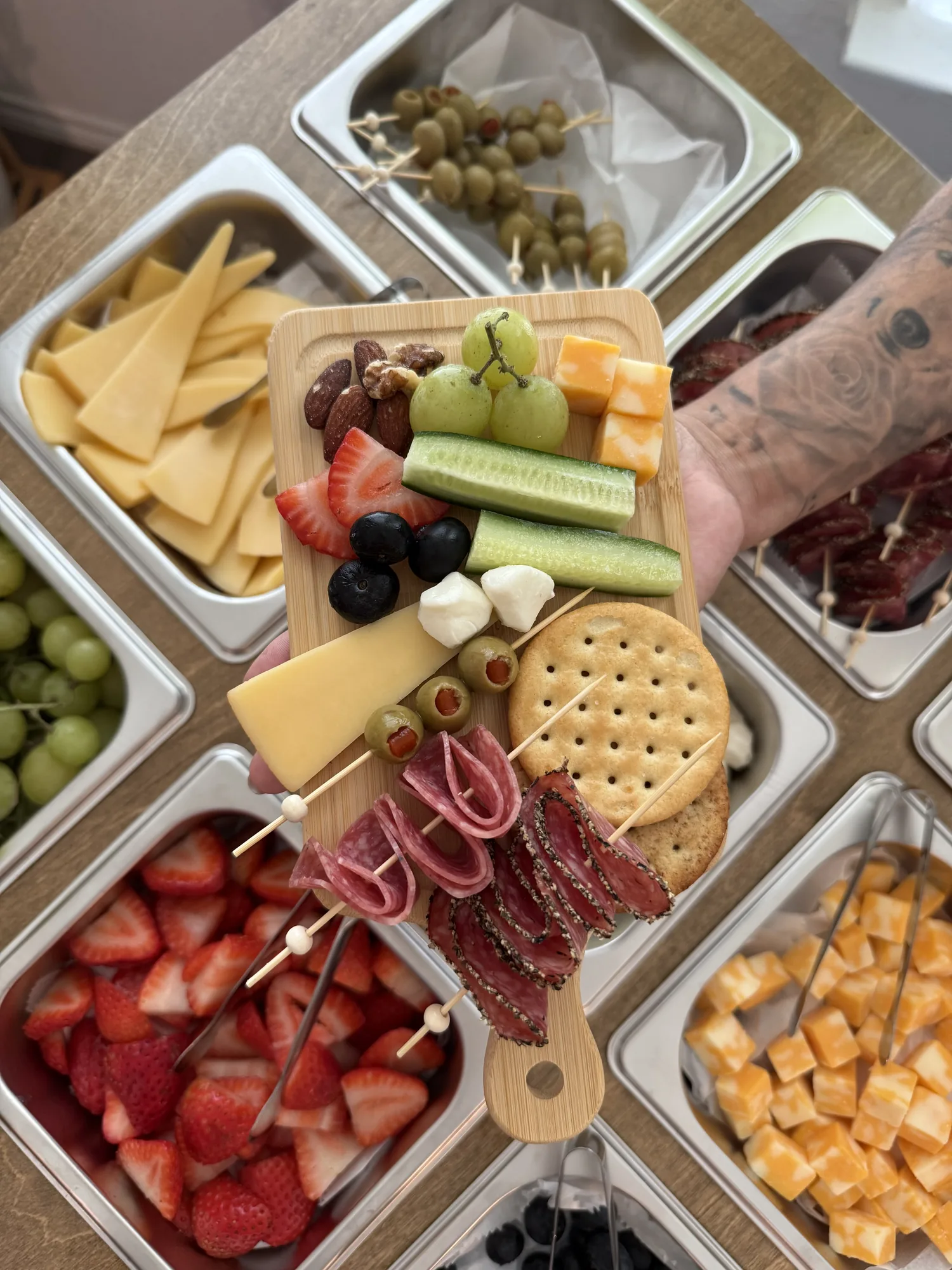 Mini charcuterie board with gouda, salami, grapes, strawberries, olives and crackers held above the cart's pans