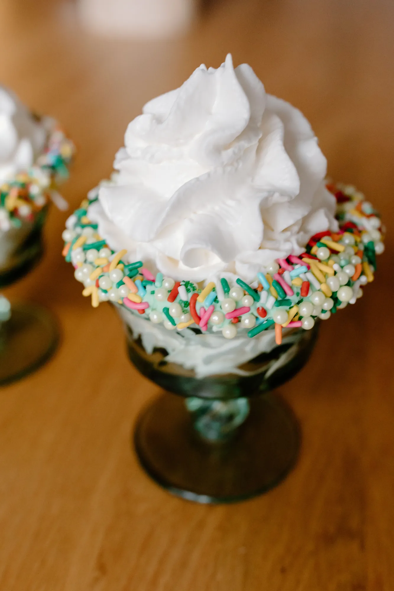 Sundae glass with a sprinkle-coated rim piled high with whipped cream